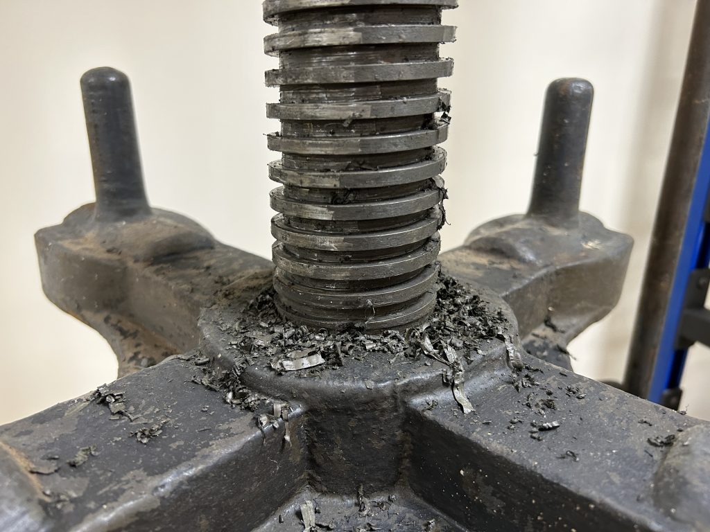 The press screw showing dried lubricant being scraped off