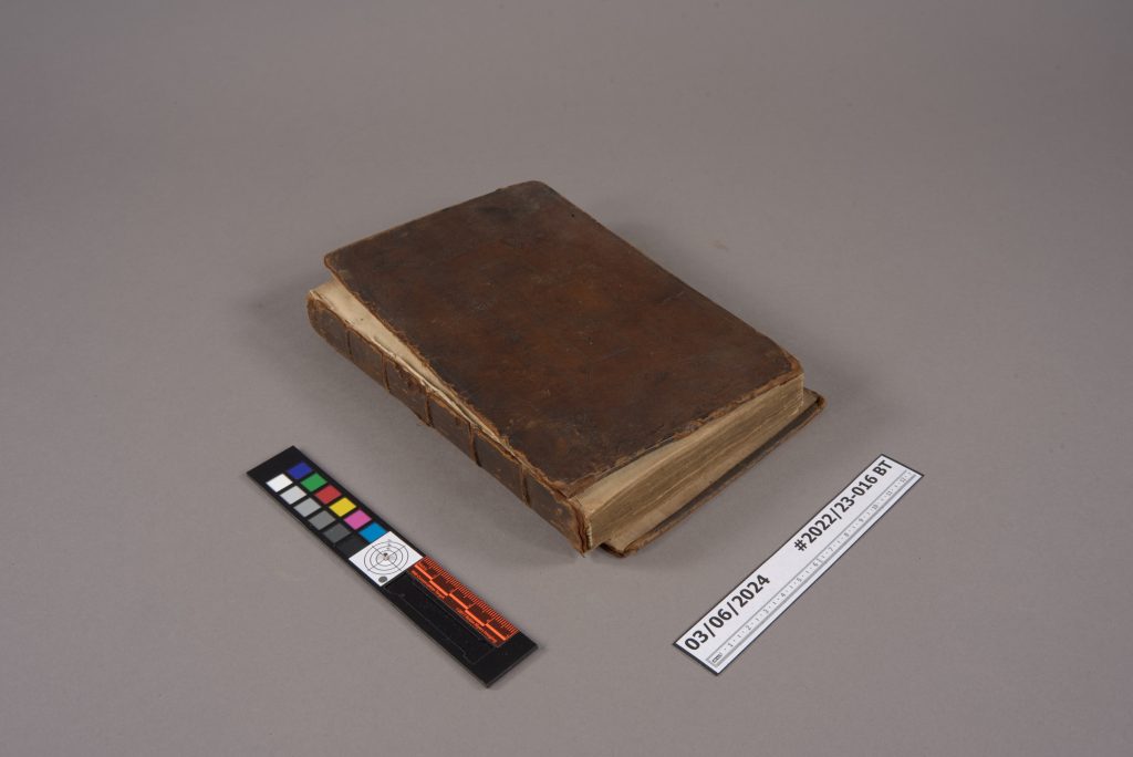 A brown leather book sitting on a table surface in 3/4 view, showing detached boards. 