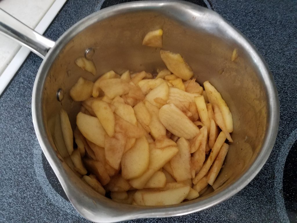 photograph showing thinly sliced apples in a pot on a stove top
