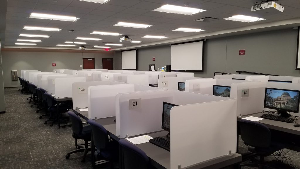 A university computer lab with dividers separating each desktop computer. Each computer has a LCD monitor and no towers are visible.