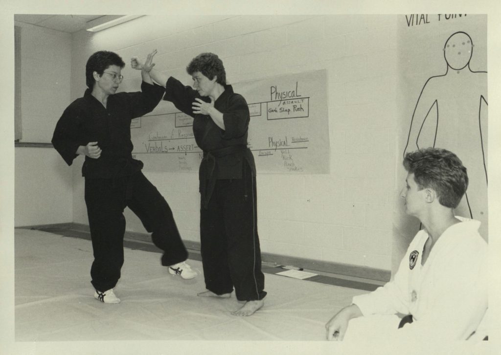 Two women in black gis demonstrating moves. 