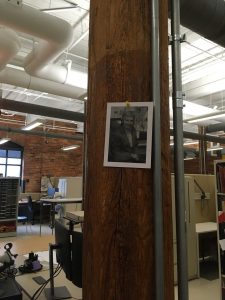 Image of a wooden column with a photograph of Ann Baker thumbtacked to the column.