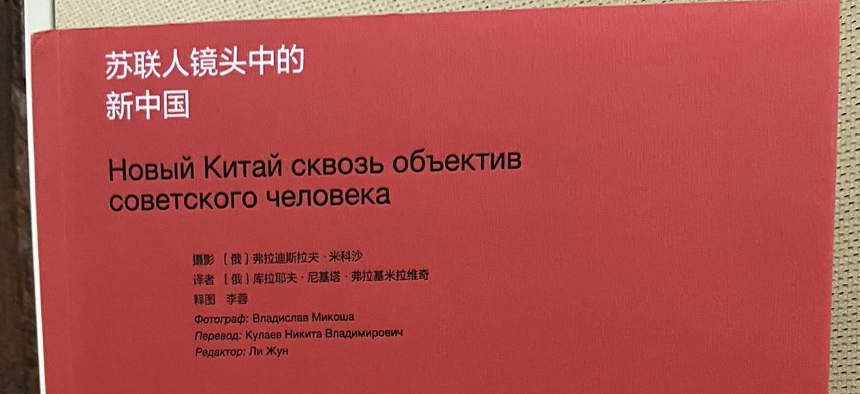 A red book standing up on a desk, with the title 苏联人镜头中的新中国 = Новый Китай сквозь объектив Советского человека in black on the cover.
