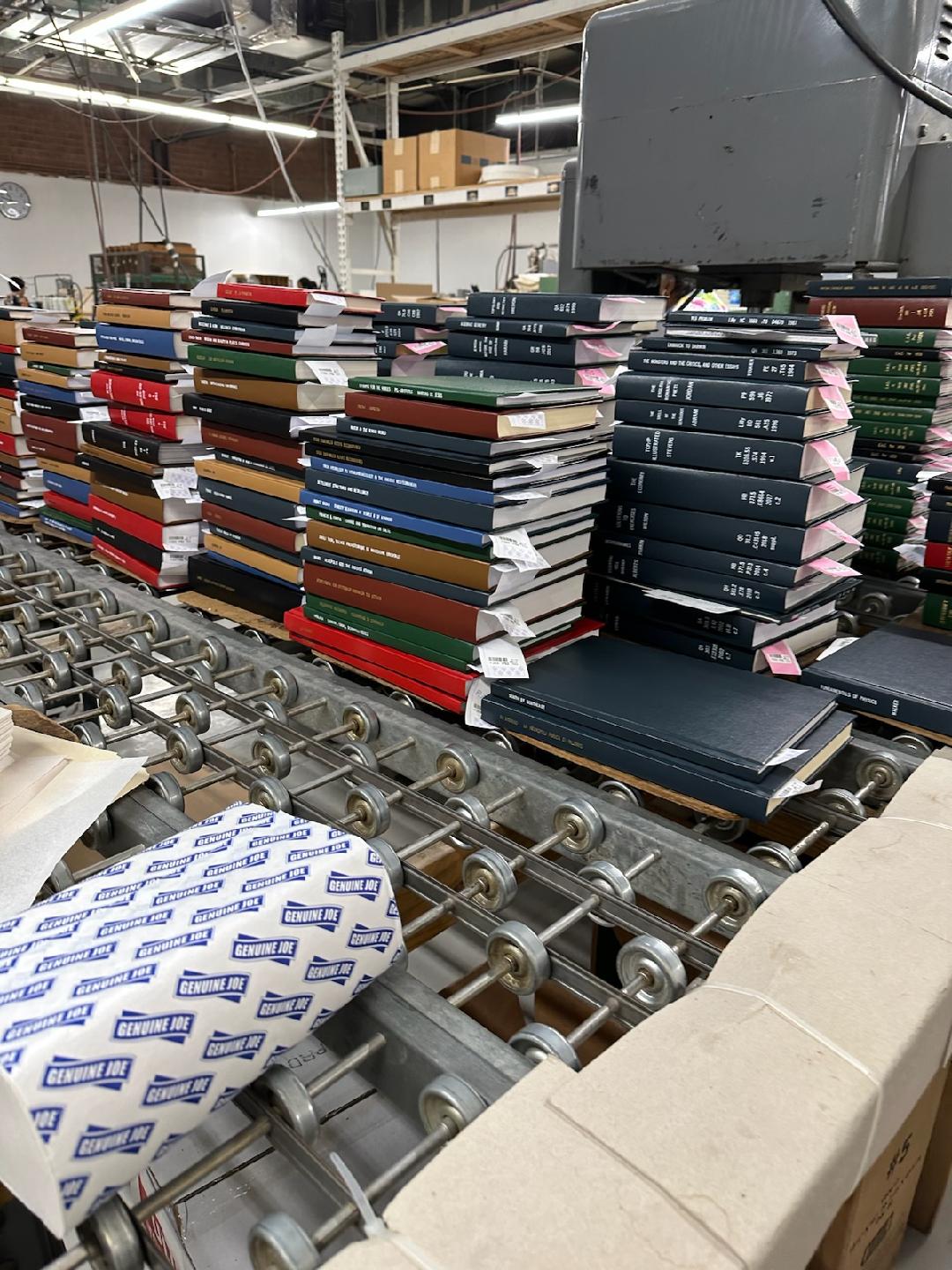 Stacks of commercially-bound books for the libraries with different cover colors.