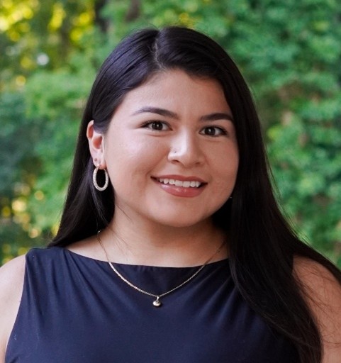 Headshot of Melina Flores, a woman wearing a dark blue sleeveless top, with long dark hair.