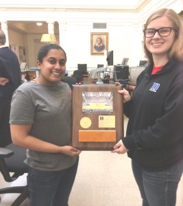 Two women students holding plaque