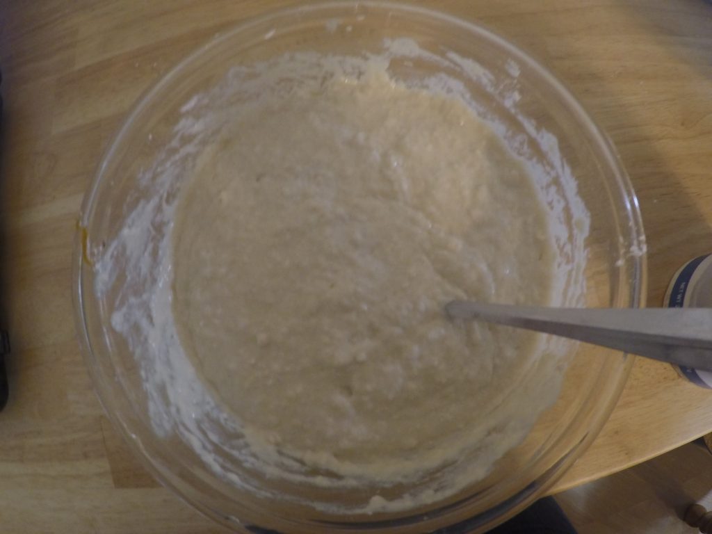Photograph of wet dough in a glass mixing bowl